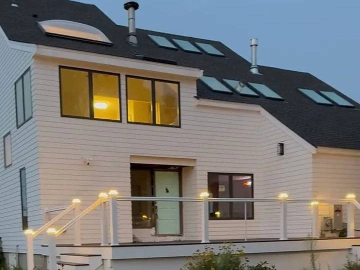 Deck post cap lights installed on a home railing at dusk